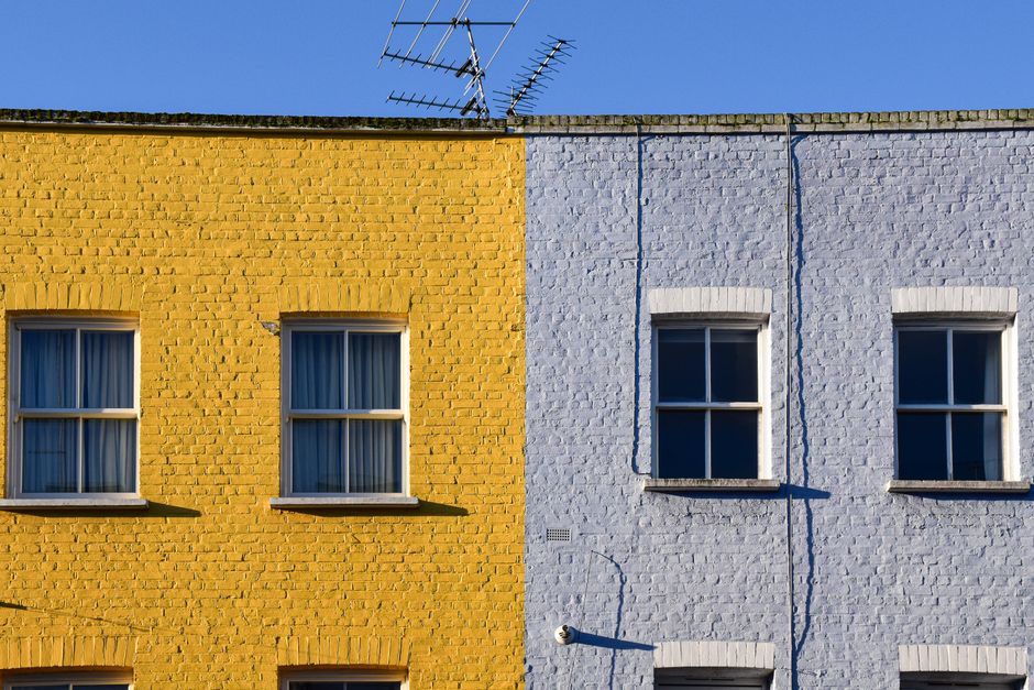Two adjoining terraced house fronts painted in contrasting yellow and pale blue
