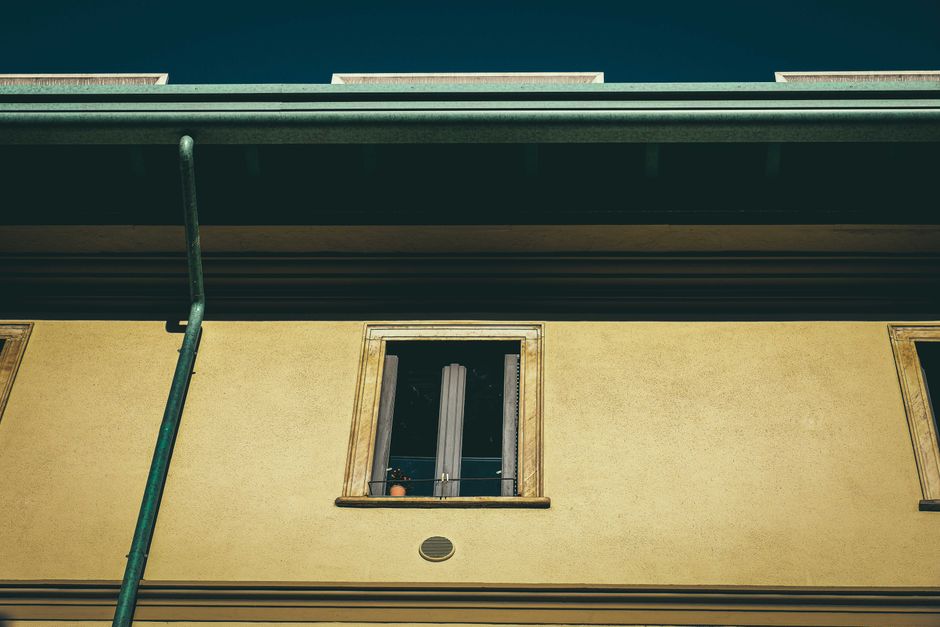 View looking up at a house eaves and guttering above a first-floor window